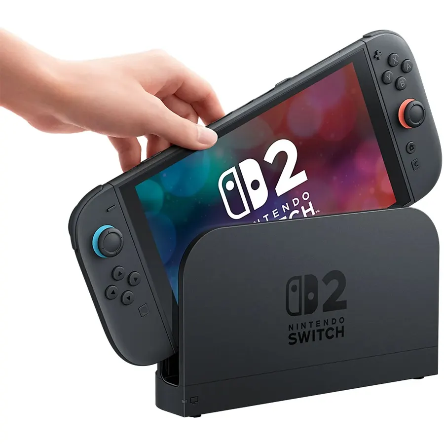 Eine Person steckt die NINTENDO Switch 2 Konsole mit farbigen Joy-Con-Controllern in die Dockingstation, das Display zeigt das Switch 2 Logo.