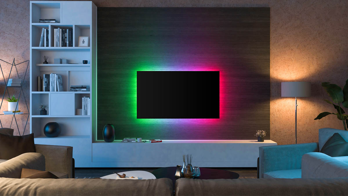 Ein Wohnzimmer mit Sofa, Tisch und Fernseher mit stimmungsvoller RGB Beleuchtung hinter dem TV und Lampen mit warmen Licht.