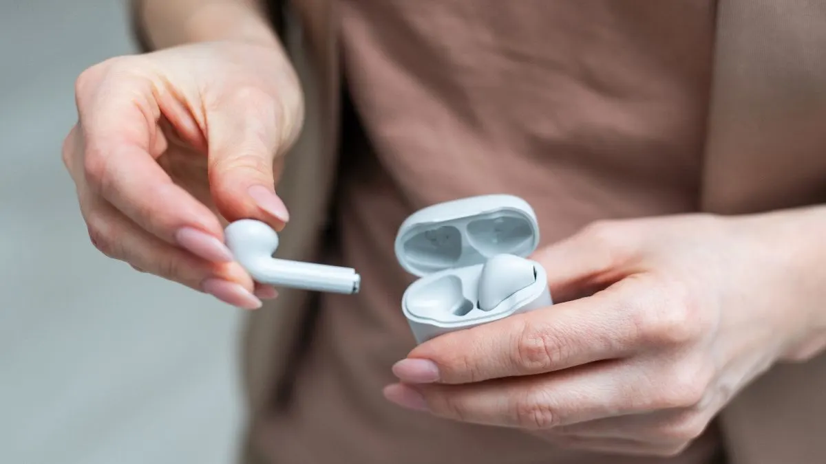 Eine Person holt In-Ear-Kopfhörer aus einem Ladecase heraus.