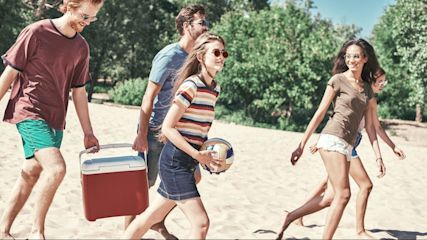 Eine_Gruppe_von_Freunden_am_Strand_mit_Kuehlbox