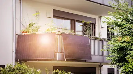 Ein Balkonkraftwerk ist an der Ecke des Geländers auf einem Balkon befestigt.