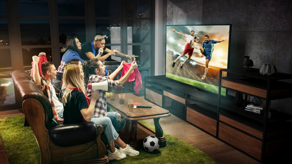 Eine Gruppe Freunde schaut Fußball auf einem Fernseher