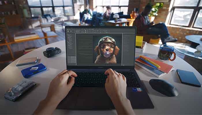 Ego-Perspektive eines Mannes, der vor seinem Laptop sitzt. Auf dem Bildschirm ist ein Fotobearbeitungsprogramm zu sehen.