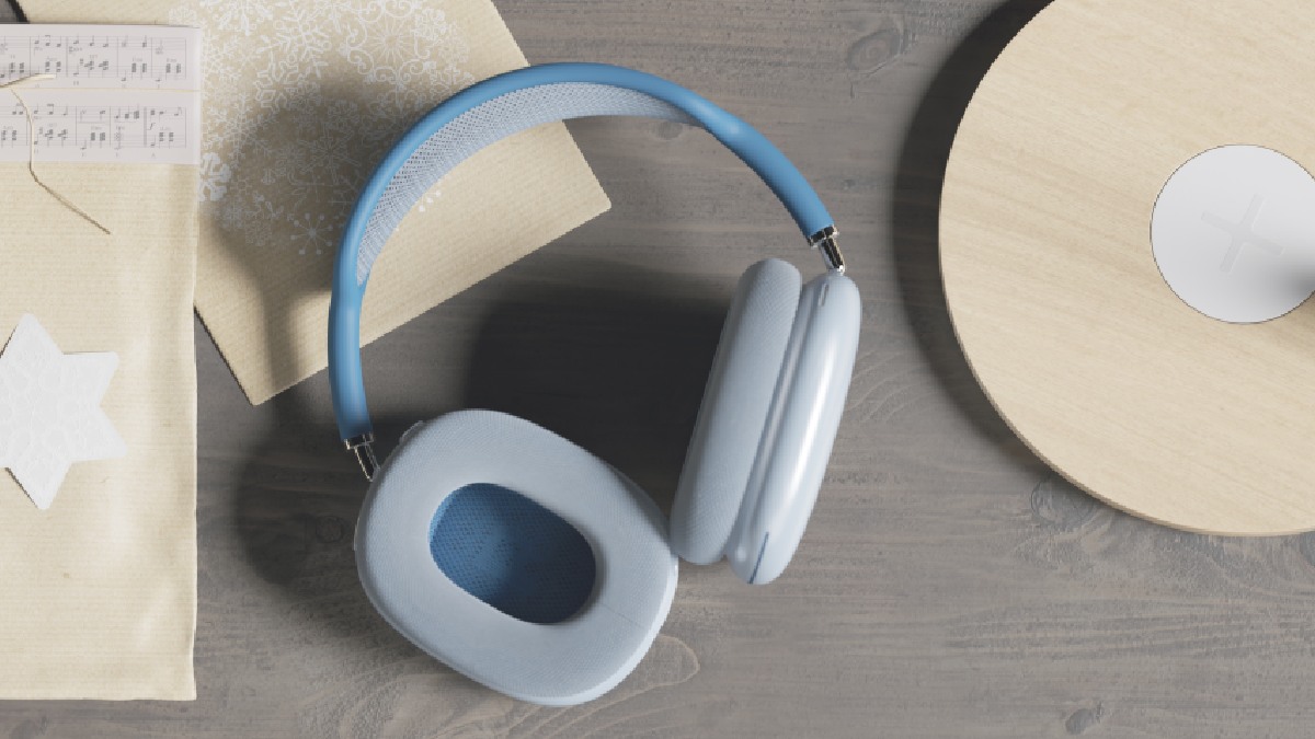 Auf einem grauen Tisch liegen blaue Kopfhörer, ein Notenblatt, ein Brief und ein runder Holzgegenstand.