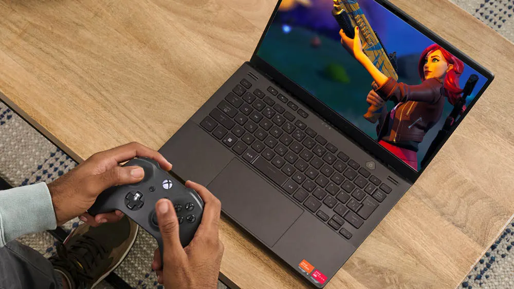 Eine Person spielt mit einem Xbox-Controller ein Videospiel auf einem Laptop auf einem Holztisch.