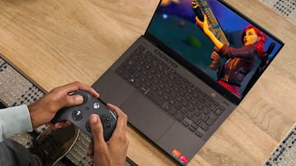 Ein Mann spielt Fortnite auf einem Laptop mit Controller.
