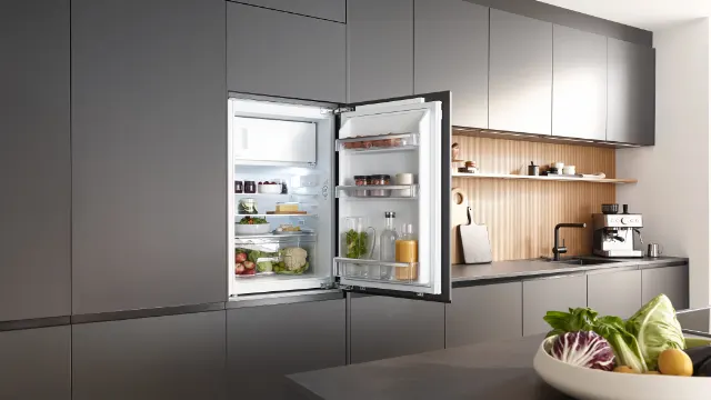 Offener KBK 8811 E DOD Einbaukühlschrank in moderner Küche, gefüllt mit Lebensmitteln, LED-Innenbeleuchtung sichtbar.