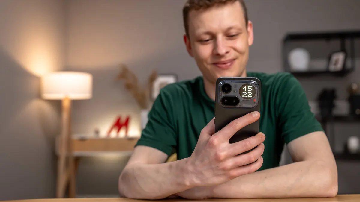 Alex sitzt an einem Tisch und scrollt auf dem Nothing Phone (4a) Pro.