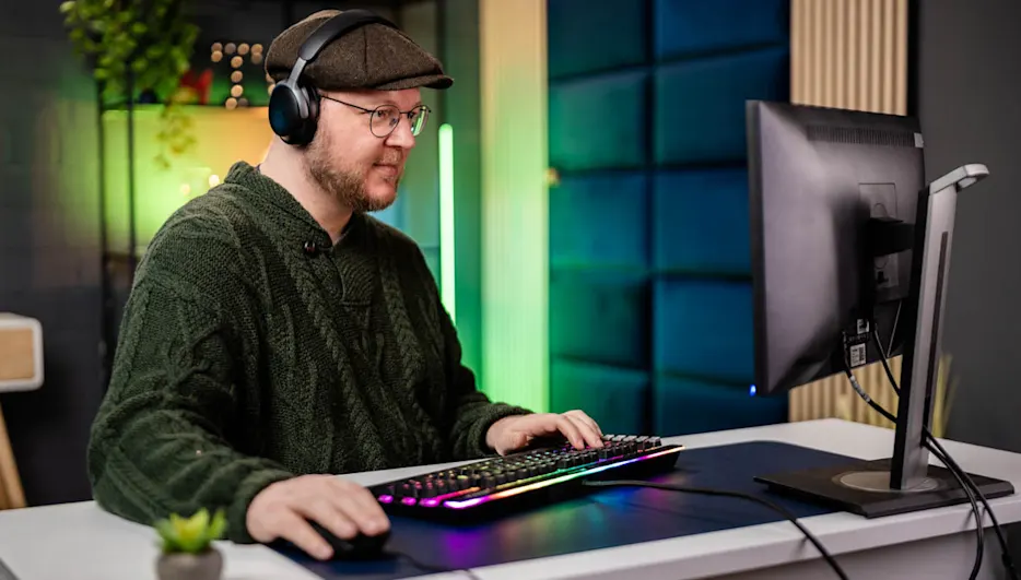 Andreas spielt mit einer leuchtenden mechanischen Tastatur ein PC-Spiel.