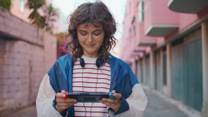 Eine junge Frau mit der Handheld-Konsole Nintendo Switch in der Hand.