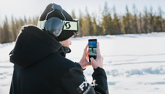 Person mit Mütze und Skibrille fotografiert mit Galaxy S26 in verschneiter Landschaft; auf dem Display steht eine Person auf dem Schnee