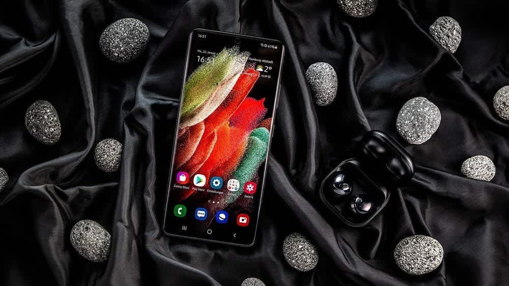 Ein Samsung Galaxy S21 Ultra, Galaxy Buds und Steine liegen auf einem schwarzen Tuch.