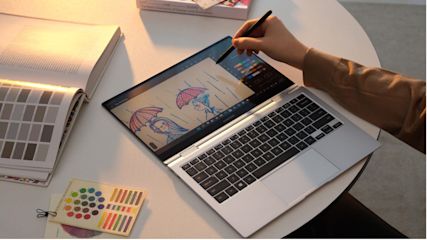 Eine Hand zeichnet auf dem Samsung Galaxy Book2 Pro, welches auf einem Tisch liegt