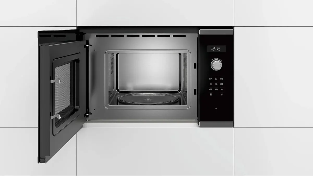 Die Einbaumikrowelle Bosch BFL524MS0 ist in eine weiße Schrankwand integriert, die Tür der Mikrowelle steht offen.