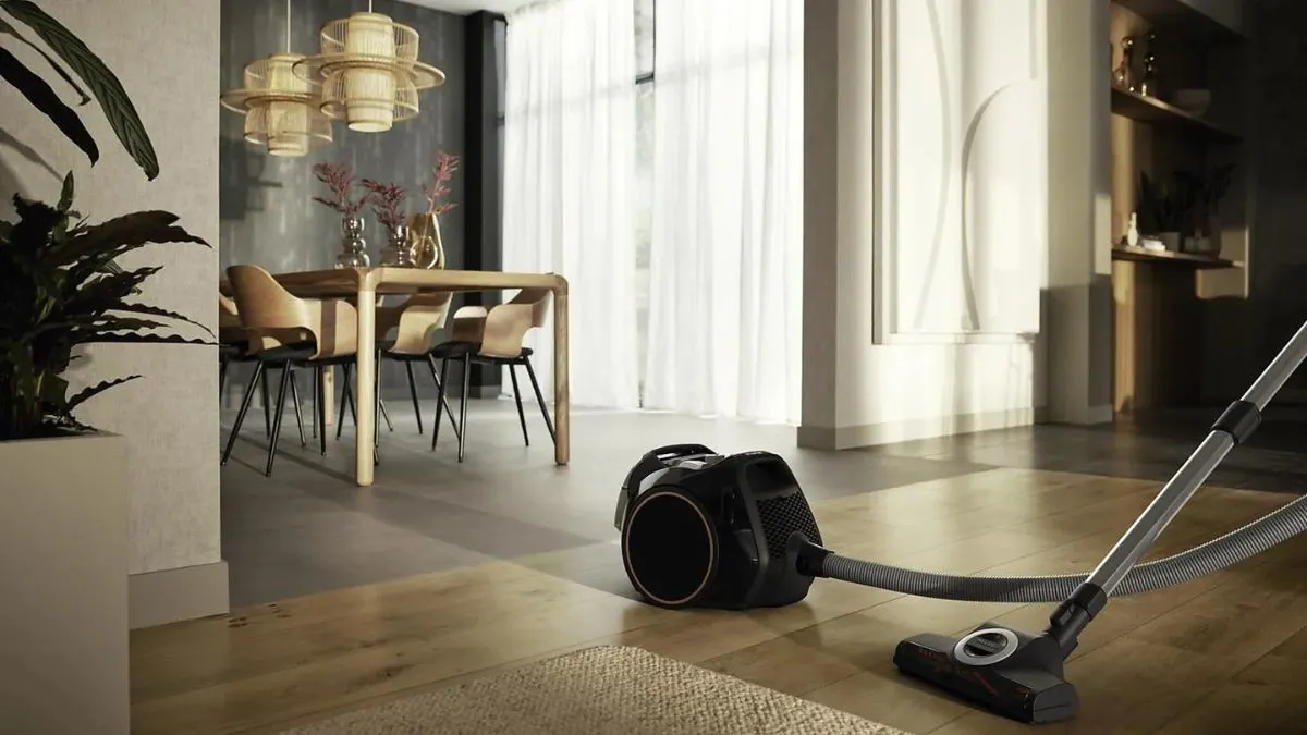 Der Staubsauger Miele Boost CX1 Cat & Dog steht auf einem Parkettboden in einem Wohnzimmer.