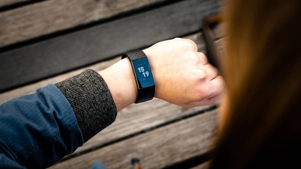 Eine Frau schaut auf ihre Fitbit Charge 3 in schwarz.