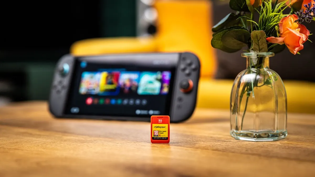 Eine Nintendo Switch 2 und eine Nintendo Switch liegen schräg versetzt auf einem Holztisch.