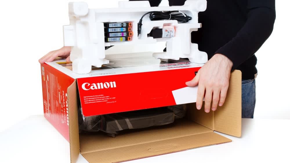 Ein Mann nimmt einen Canon-Drucker aus dem Karton.