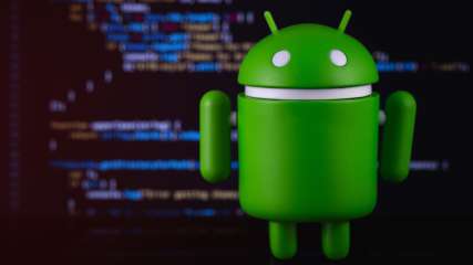 Der grüne Android-Roboter "Bugdroid" steht vor einem Bildschirm mit Programmierbefehlen.