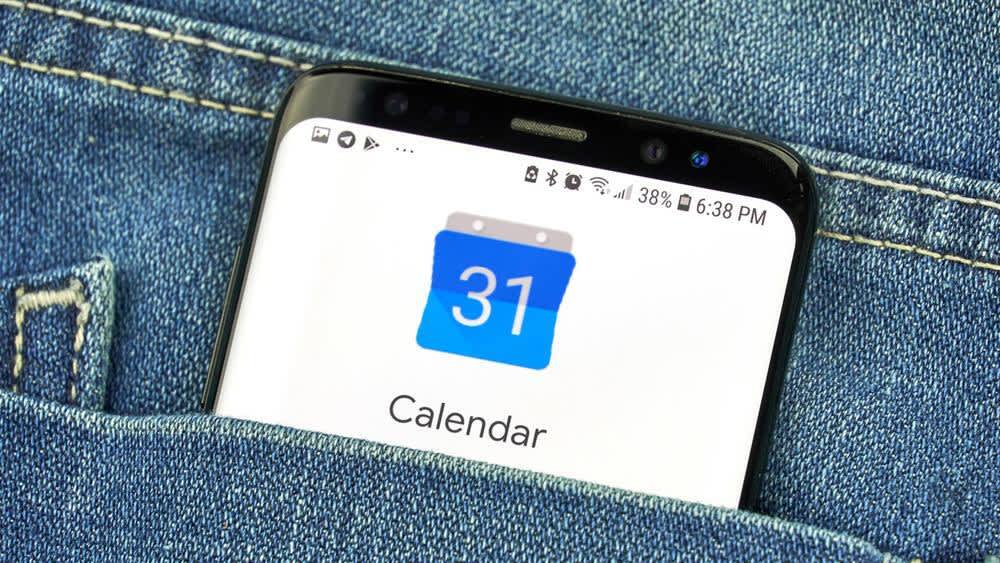 Das Logo des Google-Kalenders wird auf dem Display eines Smartphones angezeigt, das in einer Hosentasche steckt.