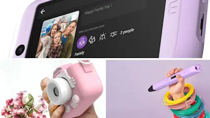 Lila Kamera zeigt Urlaubsfoto. Eine rosafarbene Kamera wird von Blumen umgeben. Eine Hand hält einen lila 3D-Stift mit Filament.