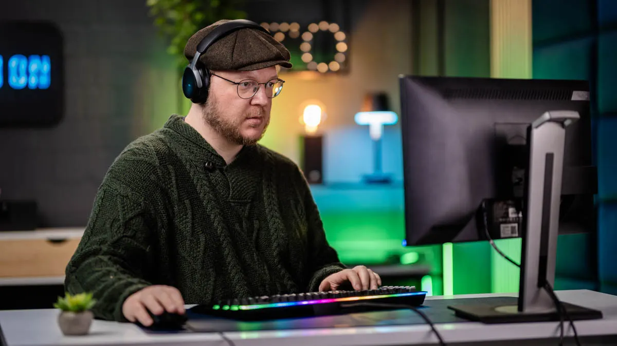 Andreas tippt auf einer mechanischen Tastatur und sitzt vor einem PC-Monitor.