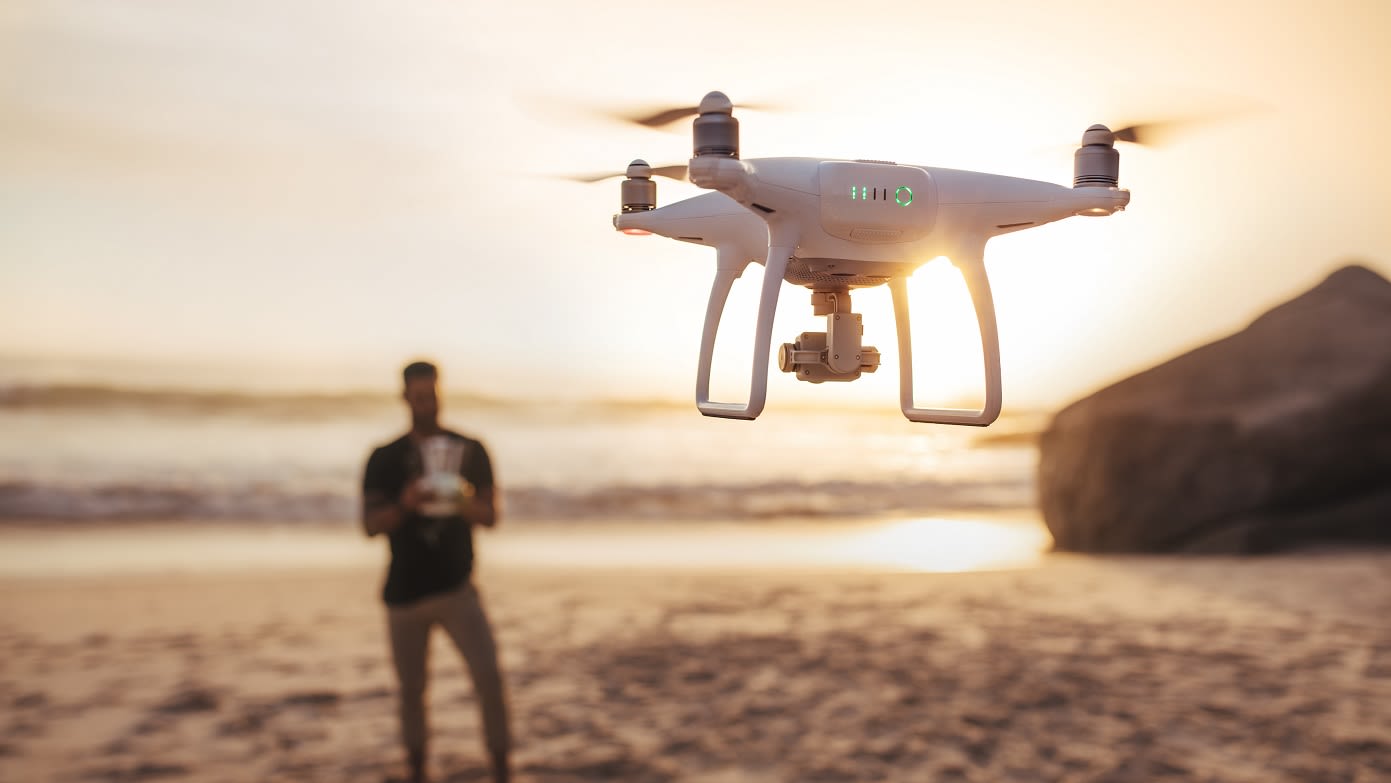 Das Fliegen einer Drohne am Strand bei Sonnenuntergang symbolisiert den DJI MINI 2 Akku Akku Grau