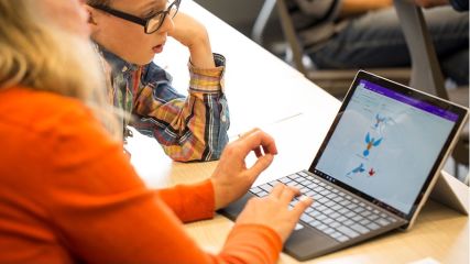 Eine Frau sitzt mit einem Jungen vor einem Microsoft Surface Laptop