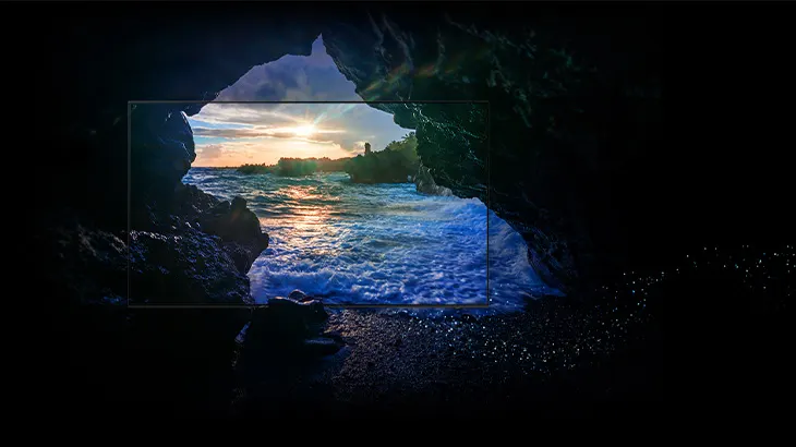 Blick aus einer dunklen Höhle auf eine atemberaubende Küstenlandschaft bei Sonnenuntergang. Das Wasser reflektiert die warmen Farben des Himmels, während Wellen sanft an den Felsen brechen. Der Rahmen um den Bildausschnitt verstärkt den Eindruck einer natürlichen Bildkomposition.