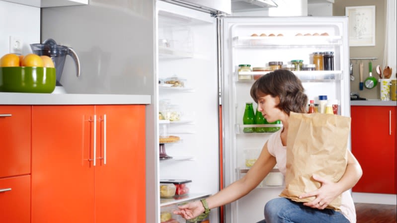 Eine Frau räumt Einkäufe in den Kühlschrank ein