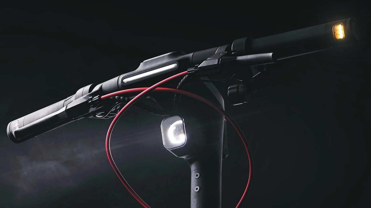 Detailansicht SEGWAY Ninebot MAX G3 D E-Scooter: beleuchteter Lenker mit Front- und seitlichen LED-Leuchten sowie rotem Bremskabel vor dunklem Hintergrund.