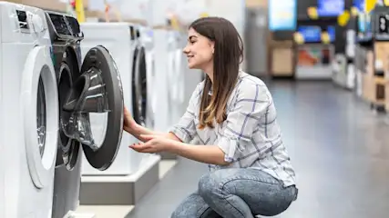 Eine Frau öffnet die Tür einer Waschmaschine im Fachhandel.