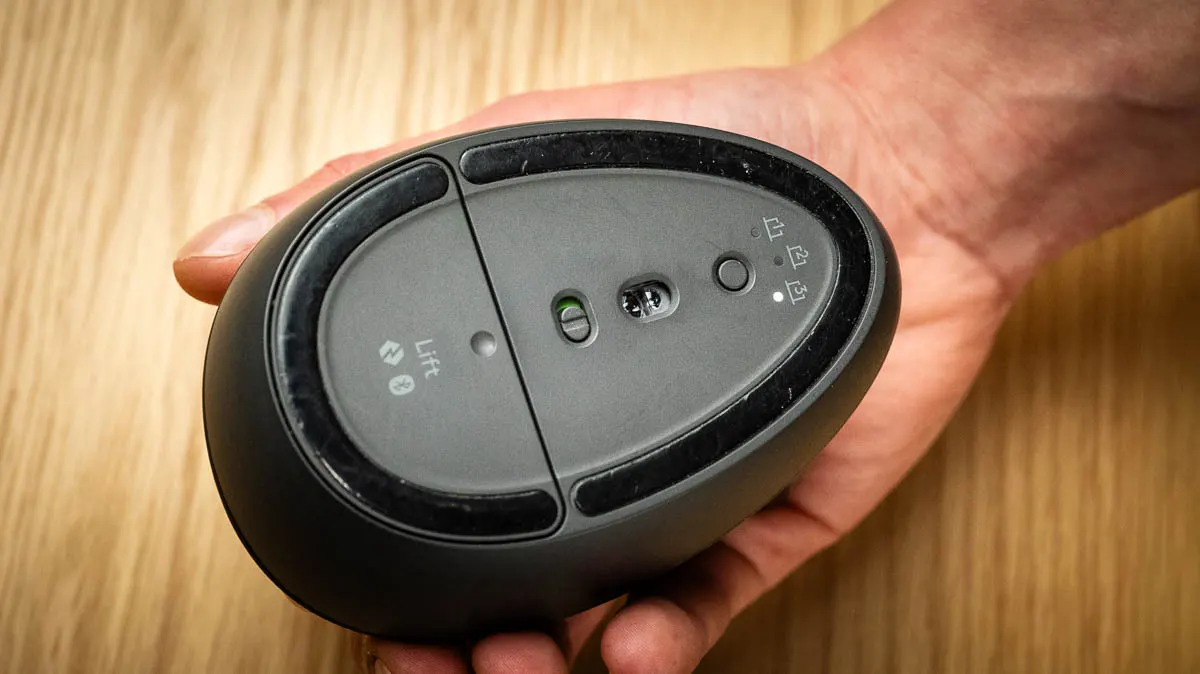 Die Unterseite der ergonomischen Maus Logitech Lift, mit der Wechseltaste für verbundene Geräte und drei LEDs.