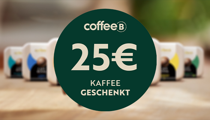 Kaffee-Pod-Packungen auf einem Holztisch. Ein grüner Kreis zeigt den Text "coffeeB 25€ Kaffee geschenkt".