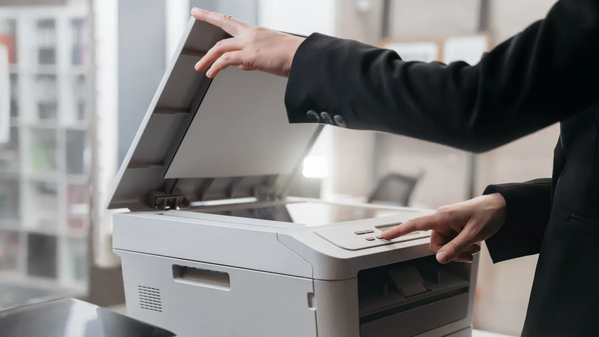 Eine Person bedient einen Laserdrucker. 