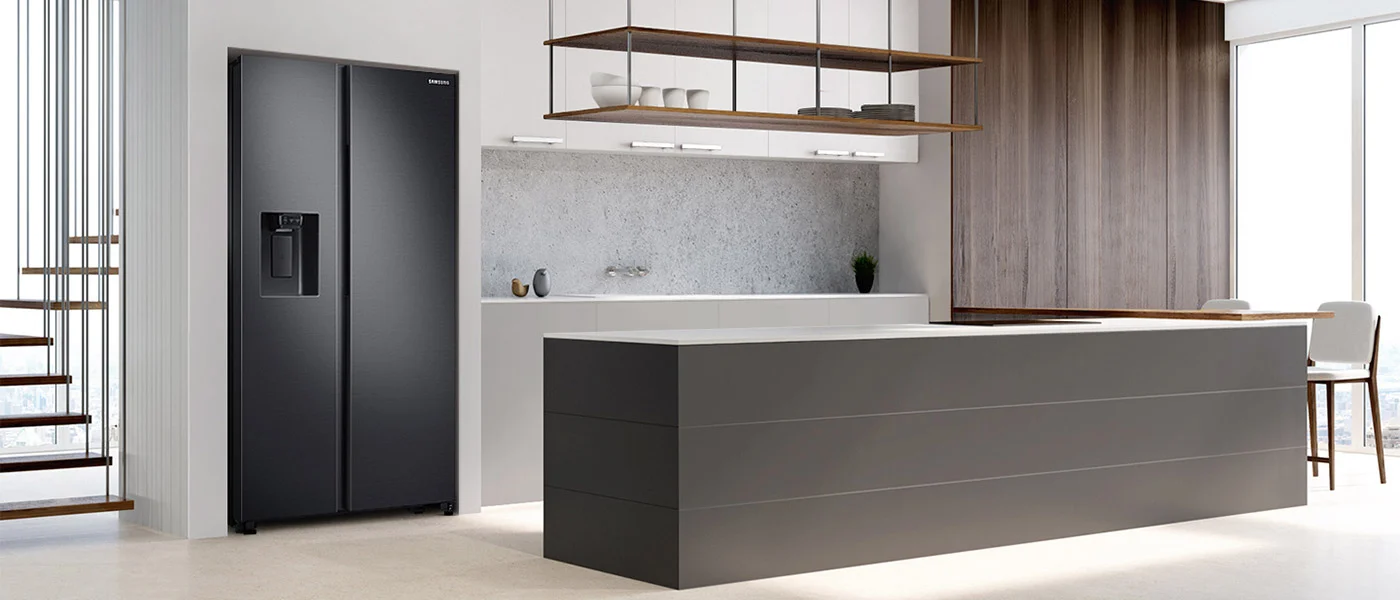 Nowoczesna kuchnia z czarną lodówką Samsung, szarą wyspą kuchenną i drewnianymi szafkami. Widoczne schody z drewnianymi stopniami.