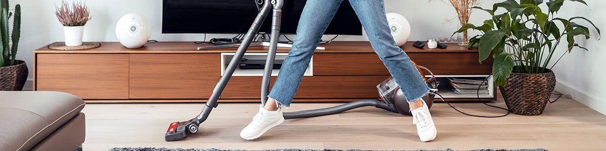 Dziewczyna odkurzająca podłogę odkurzaczem bezworkowym.