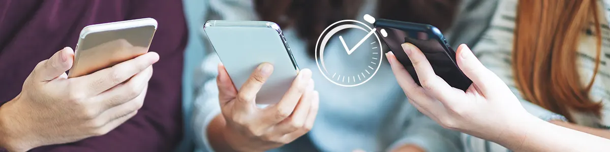 Dwóch chłopców i dziewczyna sprawdzają na swoich smartfonach czas spędzony na telefonie.