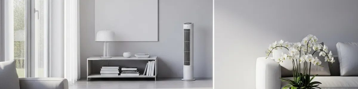 Jasne wnętrze. Widok na okno z zasłonami, regał z książkami, lampę, najlepszy wentylator kolumnowy i sofę z kwiatami. Stonowana kolorystyka.