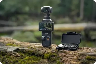 Czarny stabilizator kamery i otwarte czarne etui z trzema filtrami leżą na zewnątrz na zalesionym, zarośniętym mchem pniu.