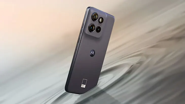 Fioletowy smartfon Motorola z czterema obiektywami aparatu i logo, leżący na tle z wzorem fal.