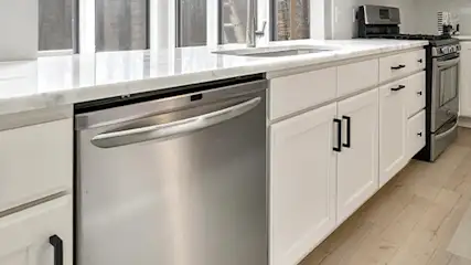 Nowoczesna zmywarka wolnostojąca pod białym blatem w eleganckiej kuchni