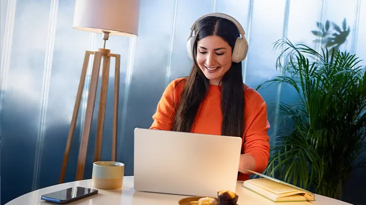 Kobieta uśmiechająca się, korzystająca z laptopa siedząc w salonie.