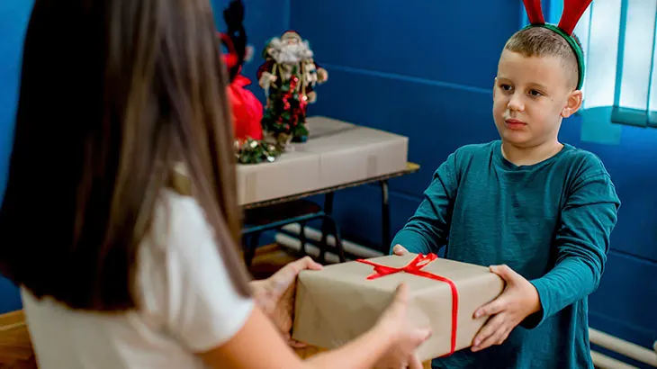 Chłopiec i dziewczynka wręczają sobie prezent w szkole.