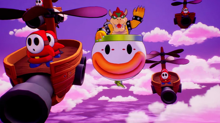 Na fioletowym niebie unoszą się postacie z gry Mario, w tym Bowser w balonie i Shy Guys na statkach z helikopterami.