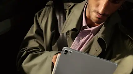Mężczyzna w płaszczu na fotelu pasażera w samochodzie z tabletem Apple iPad Pro 2025.