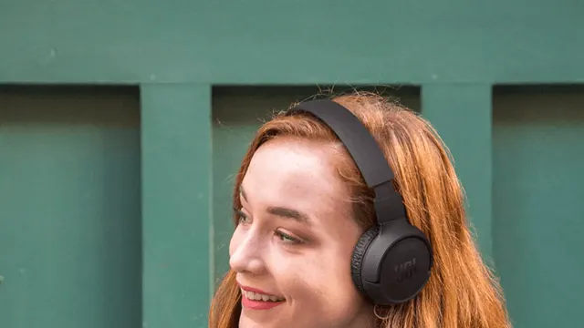 Kobieta ma na uszach czarne słuchawki. Tło jest zielone z pionowymi panelami.