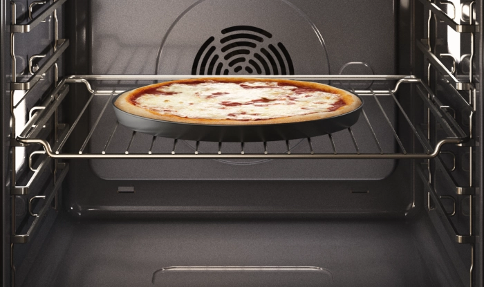 Wnętrze piekarnika i okrągła pizza.