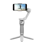 Biały stabilizator do telefonu z trzema nóżkami podtrzymującymi, na którym zamontowany jest telefon pokazujący osobę biegnącą na plaży.