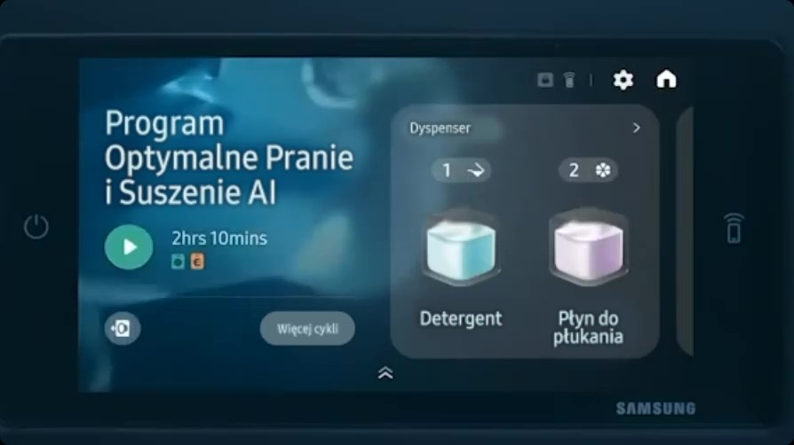 Panel dotykowy pralko‑suszarki Samsung z interfejsem po polsku. Po lewej: ‘Program Optymalne Pranie i Suszenie AI’, czas 2 godz. 10 min i przycisk start. Po prawej widżet ‘Dyspenser’ z dwiema ikonami: 1 — Detergent (niebieski), 2 — Płyn do płukania (fioletowy). U góry ikony ustawień i ekranu głównego.